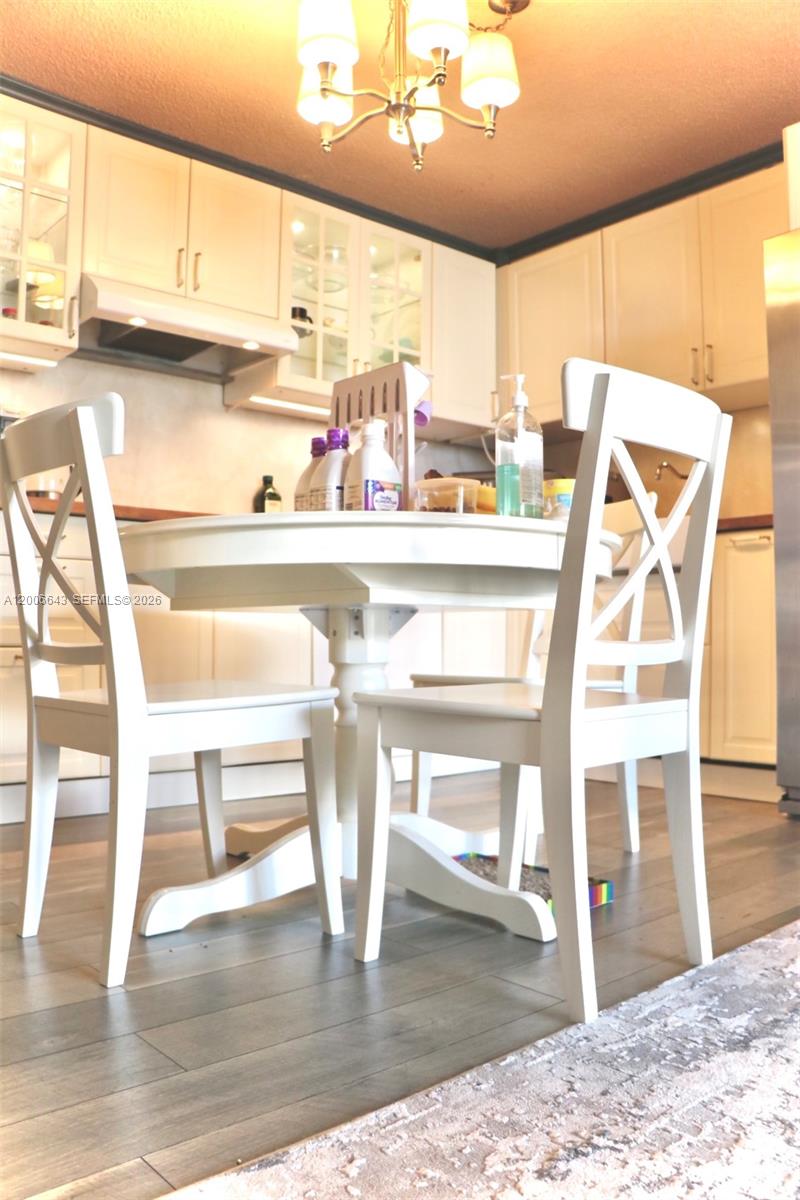 A white dining set with X-back chairs sits on a wood floor in a kitchen — HALLANDALE BEACH, FL