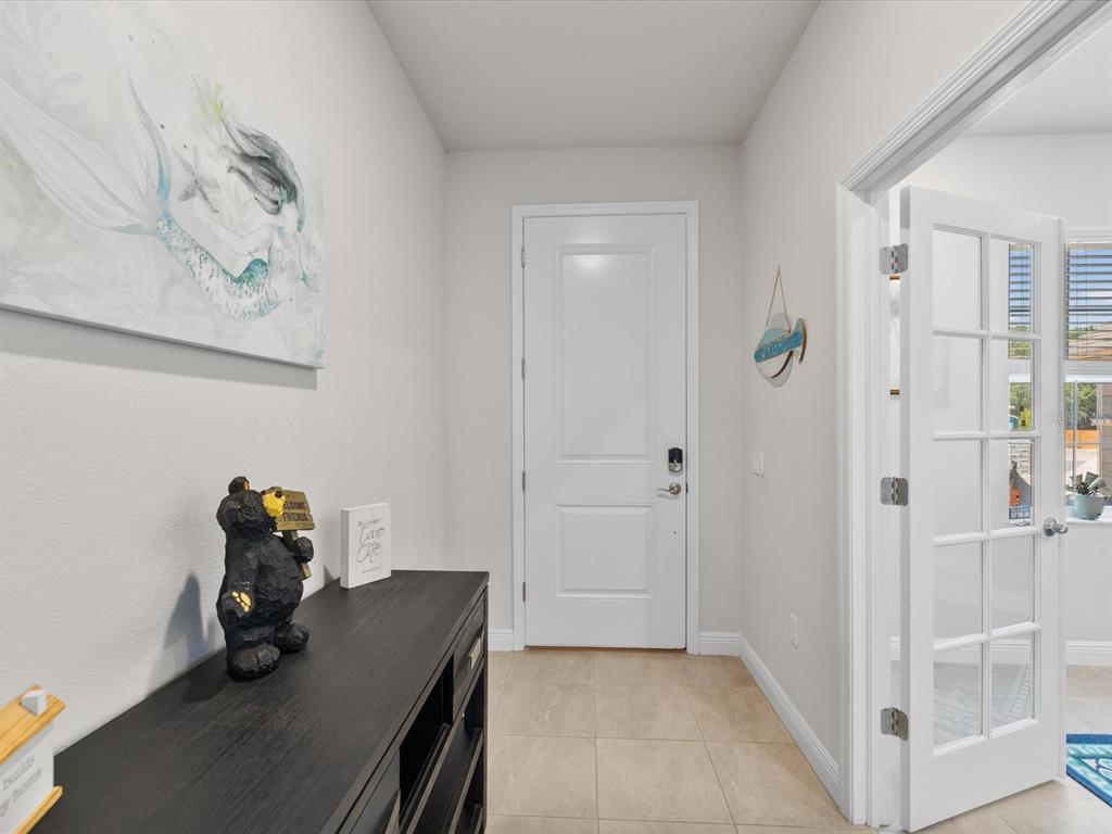 An entryway features a dark wood console table, a mermaid painting, and a glass-paneled door — 9401 HIGHLAND HILLS DRIVE, HUDSON, FL