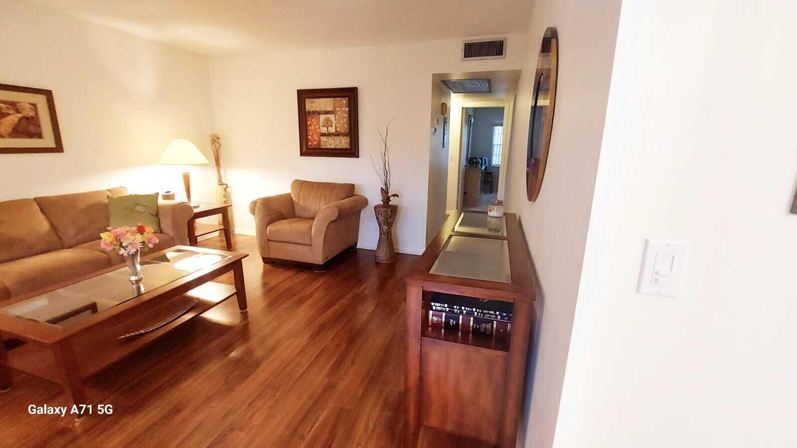 A living room features wood flooring, a tan sofa, an armchair, and a wooden console — 280 Suffolk G, Boca Raton FL 33434, BOCA RATON, FL