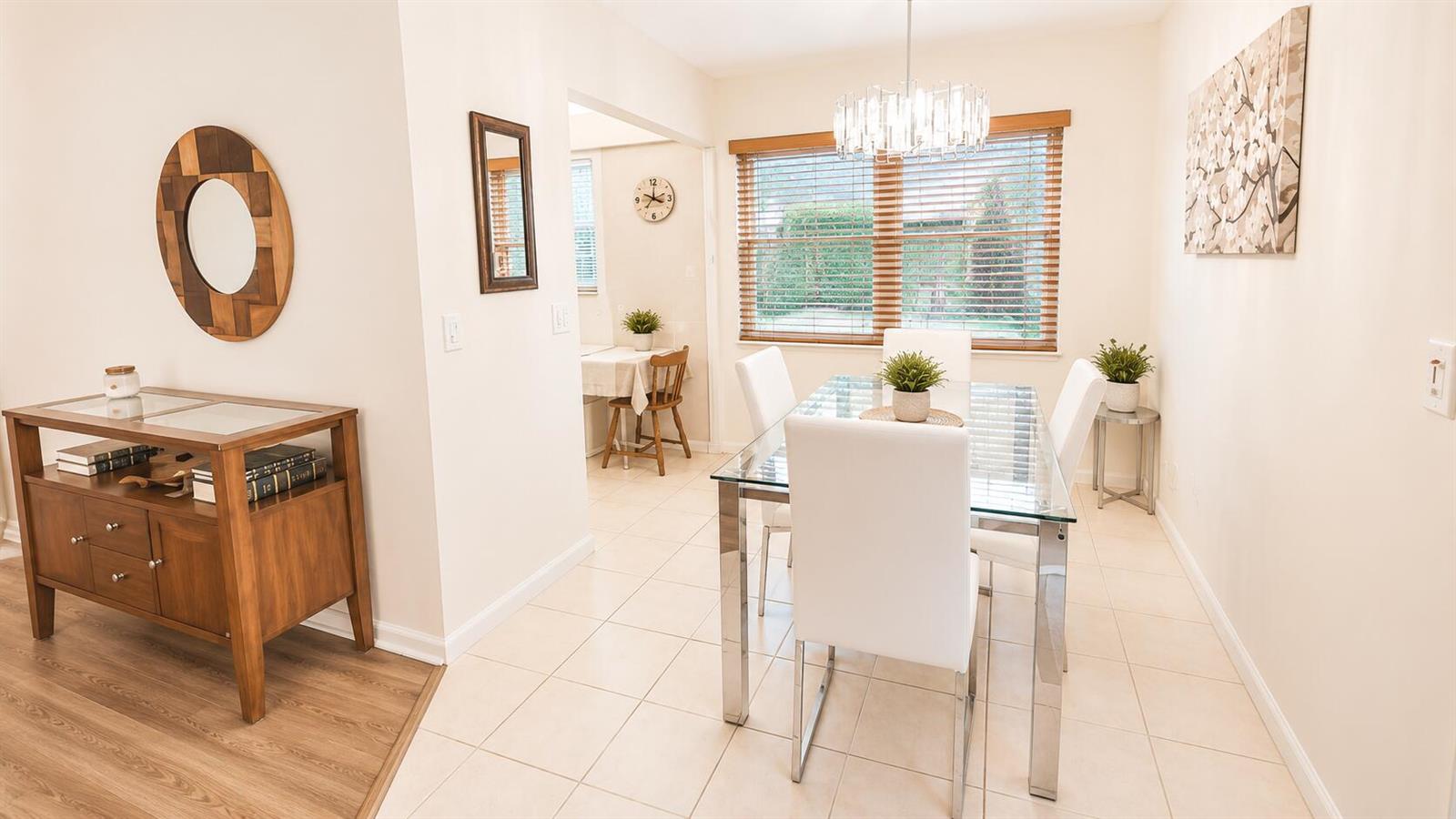 A dining room features a glass table, white chairs, tile flooring, and a wooden sideboard — 280 Suffolk G, Boca Raton FL 33434, BOCA RATON, FL