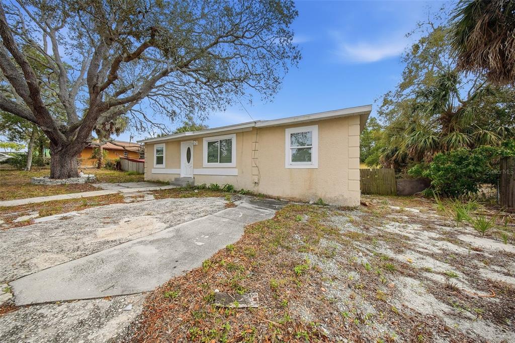 A single-story tan house with a concrete driveway and a large tree in the yard — 514 E MORGAN STREET, TARPON SPRINGS, FL