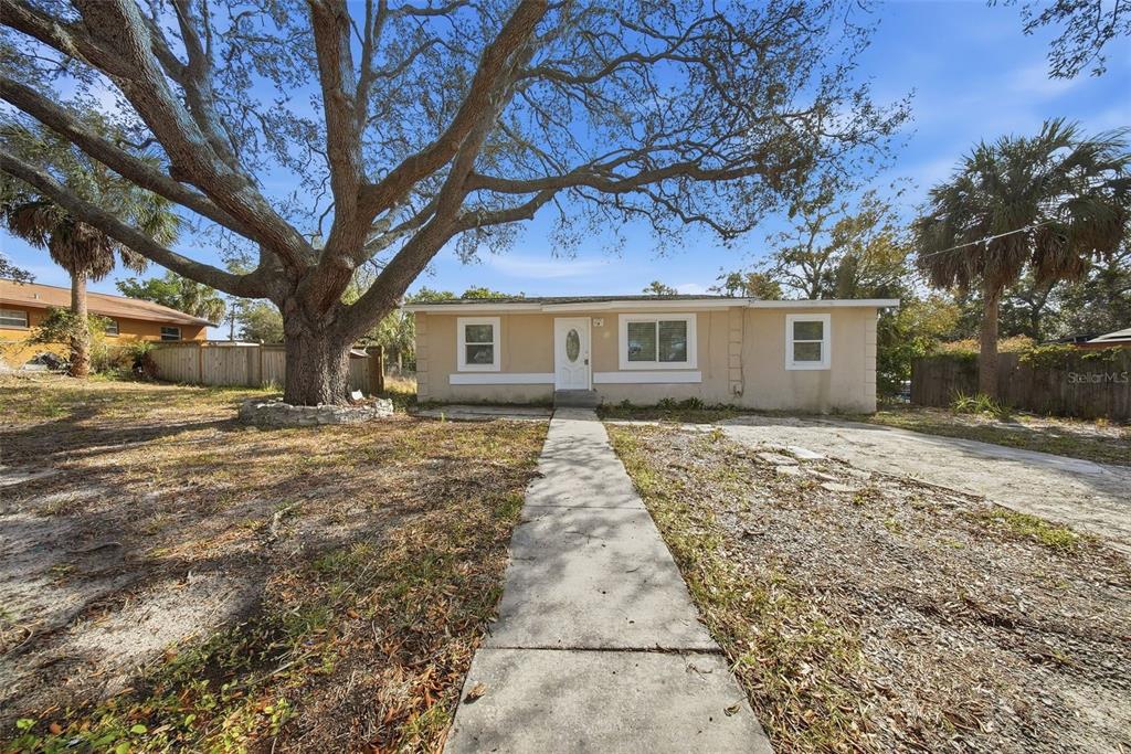 A single-story beige house with a large oak tree in the front yard — 514 E MORGAN STREET, TARPON SPRINGS, FL