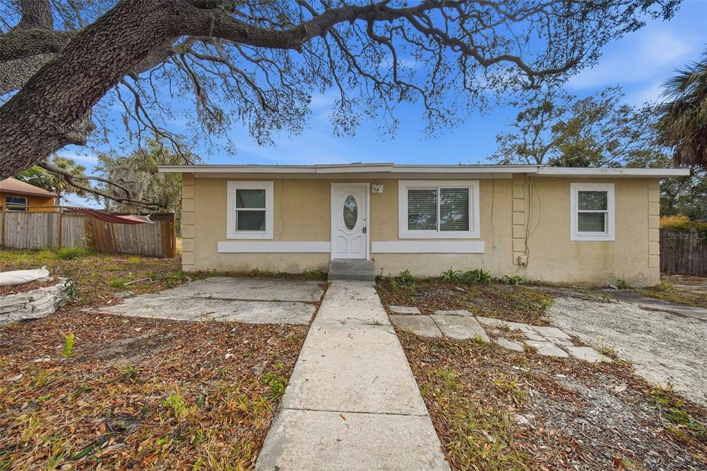 A single-story house with a beige stucco exterior, a white front door, and a walkway — 514 E MORGAN STREET, TARPON SPRINGS, FL
