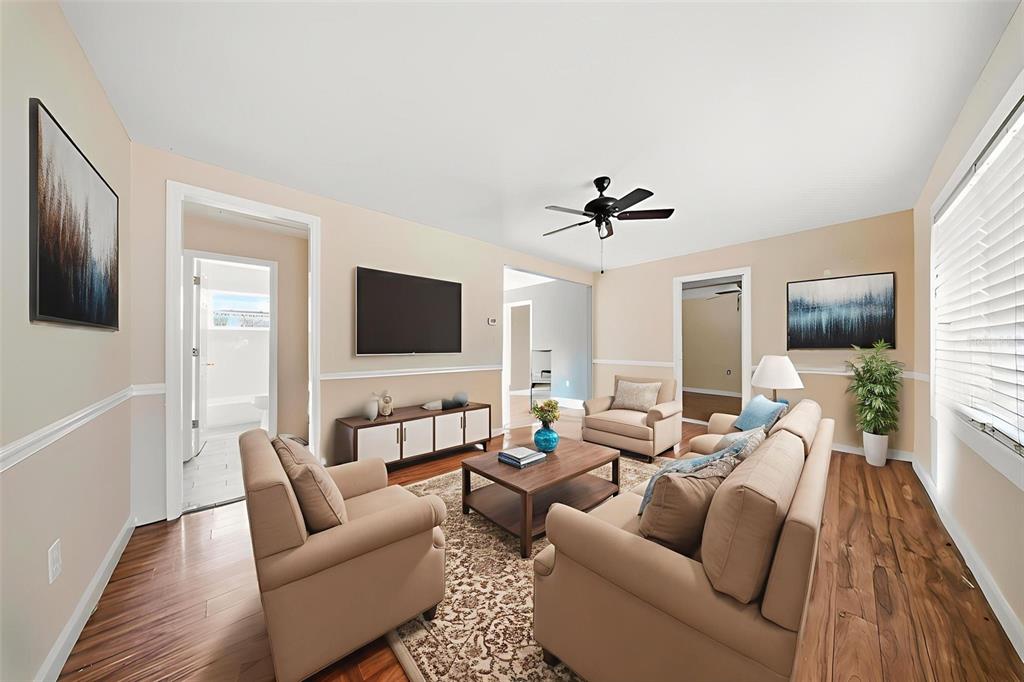 A living room features beige walls, hardwood floors, a television, and neutral-colored furniture — 514 E MORGAN STREET, TARPON SPRINGS, FL