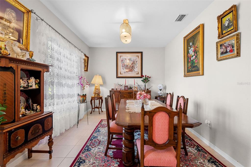 A dining room features a wooden table with pink chairs, a patterned rug, and wall art — 1751 WALTRIP STREET, NORTH PORT, FL