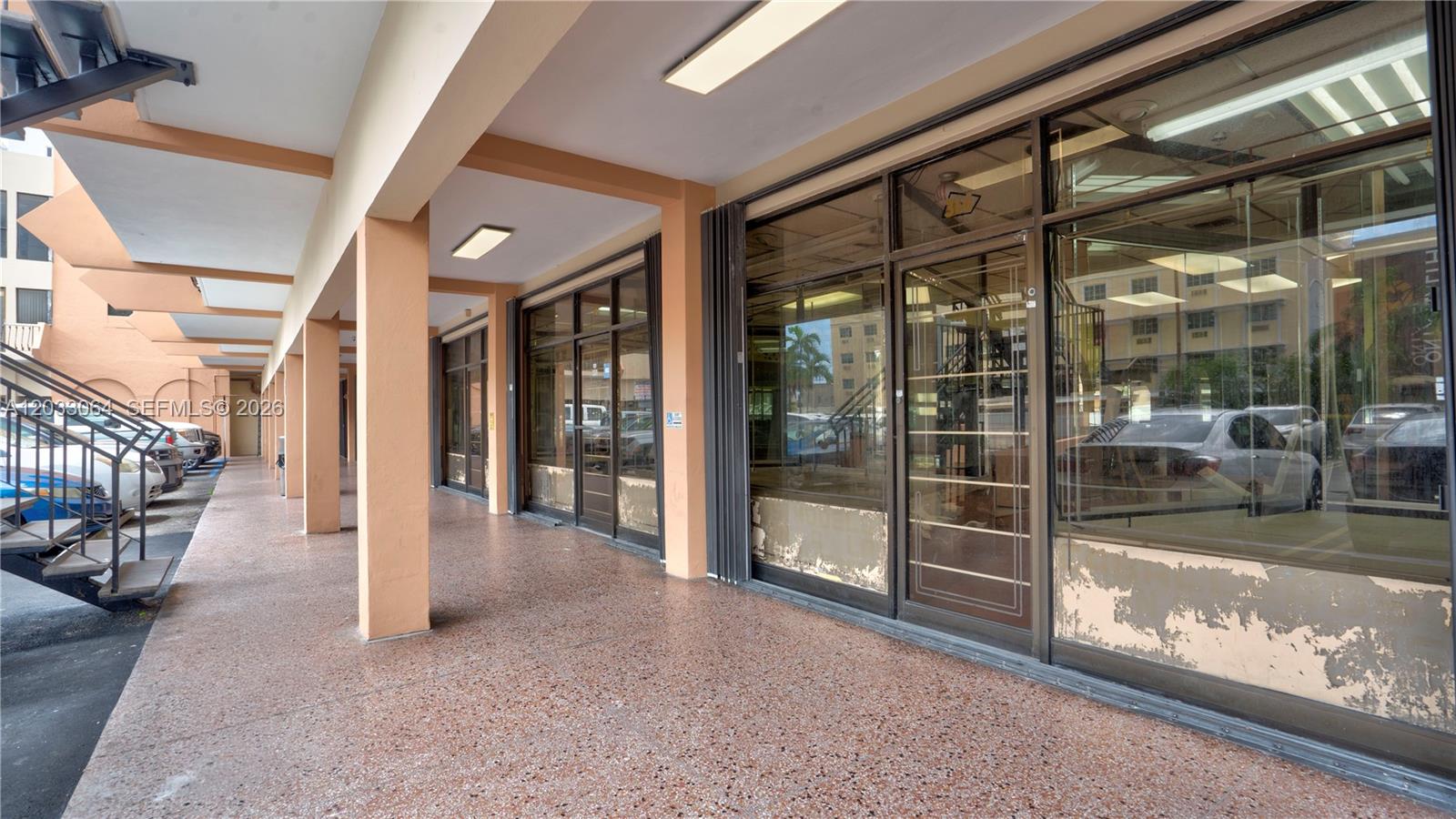 A covered outdoor walkway features tan columns and glass storefronts with peeling paint at the base — 314 SW 12 Ave, Miami FL 33130, MIAMI, FL
