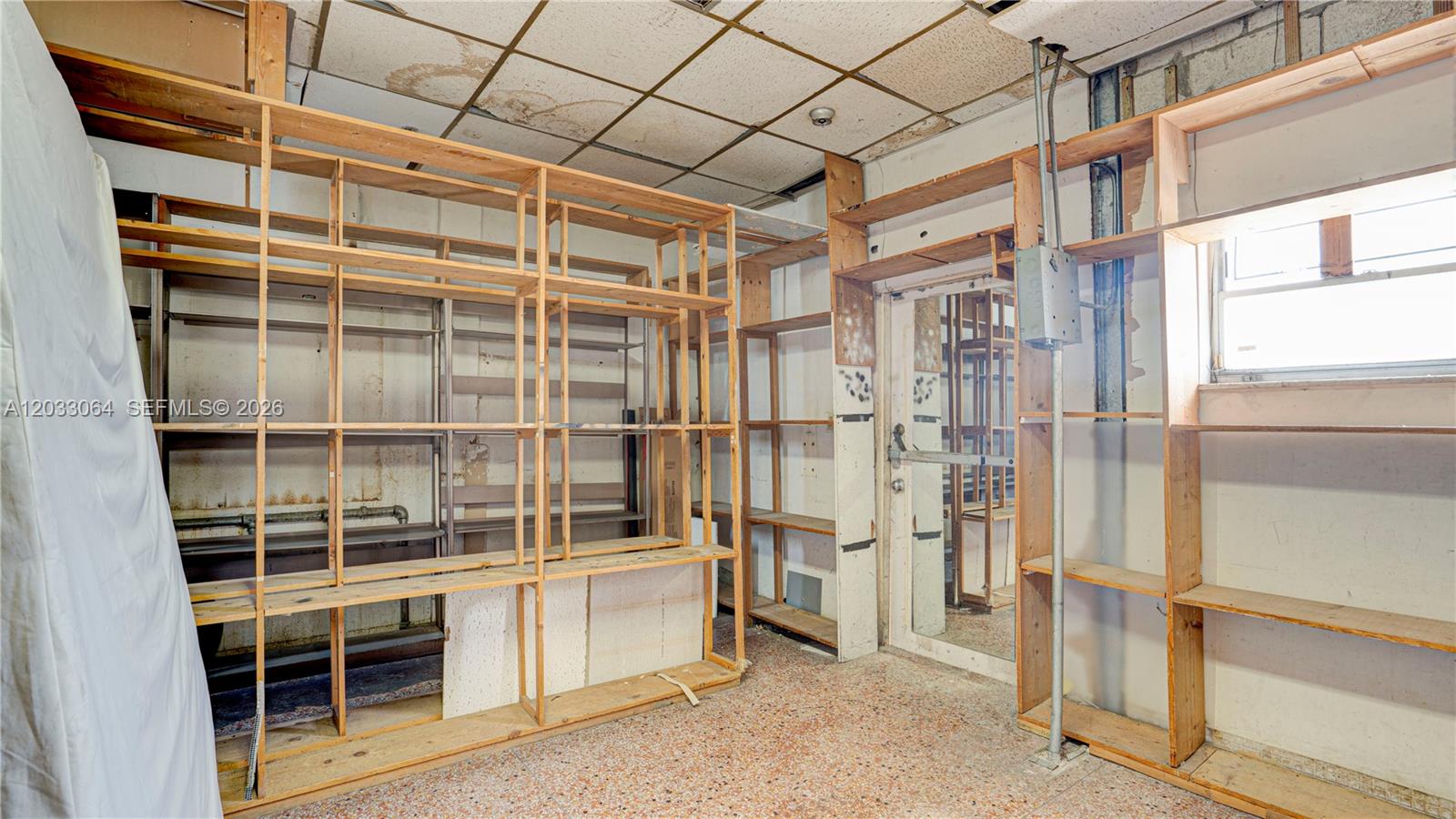 A storage room features wooden shelving units, a drop ceiling, and a terrazzo floor — 314 SW 12 Ave, Miami FL 33130, MIAMI, FL