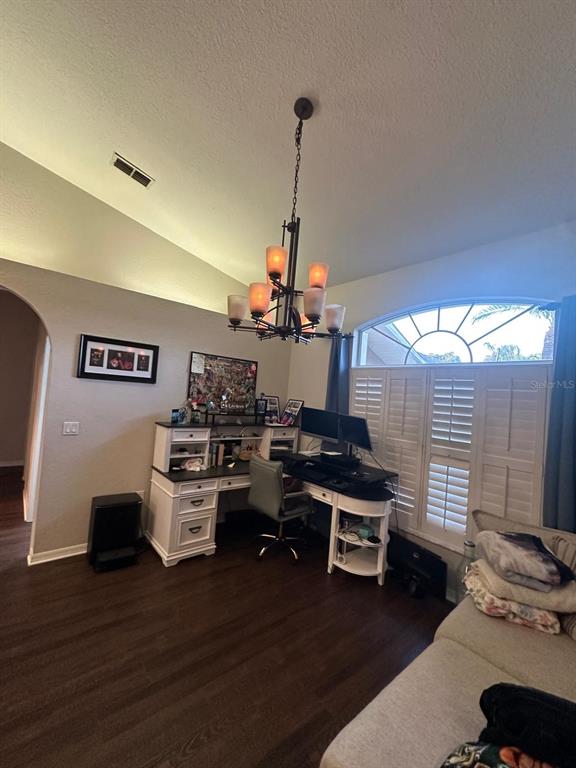 A home office features a dark wood desk, a chandelier, and plantation shutters on the window — 23218 CYPRESS TRAIL DRIVE, LUTZ, FL