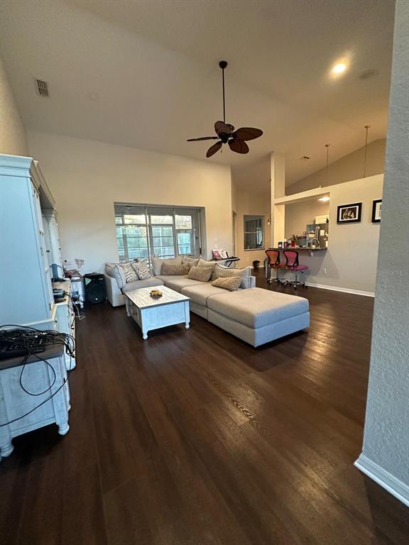 A living room with dark wood floors, a sectional sofa, and an open kitchen area — 23218 CYPRESS TRAIL DRIVE, LUTZ, FL