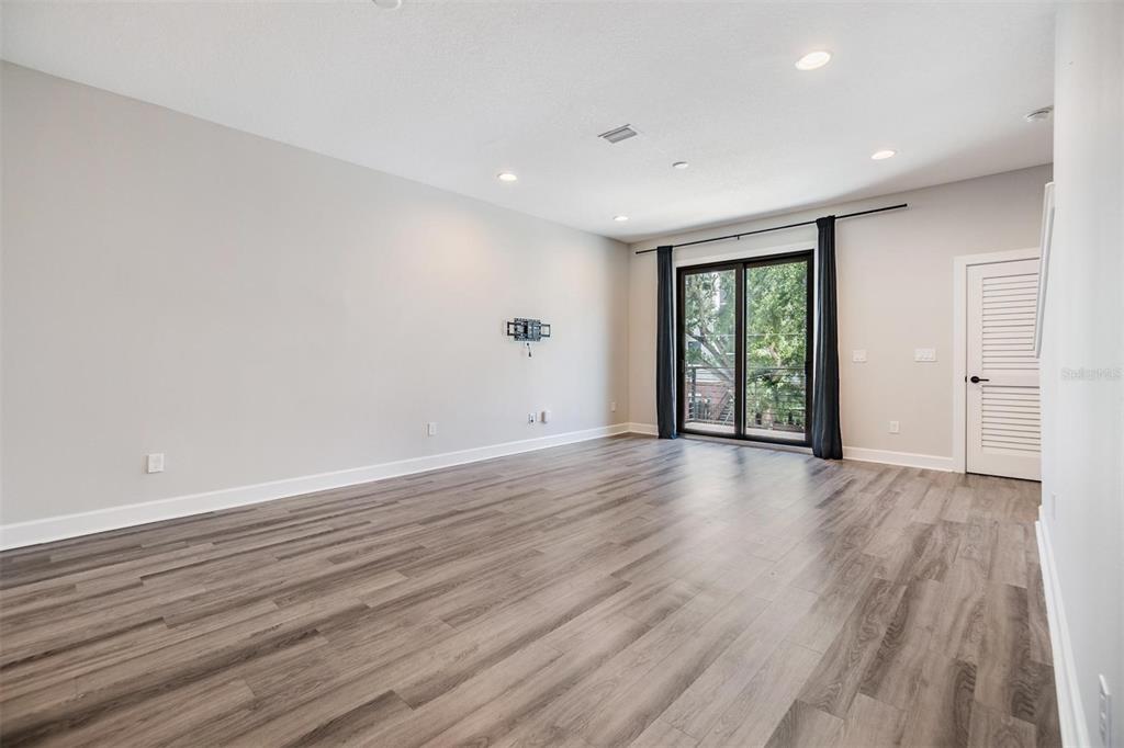 An empty living room features light gray walls, wood-look flooring, recessed lighting, and sliding glass doors — 1302 W CARMEN STREET UNIT 1, TAMPA, FL