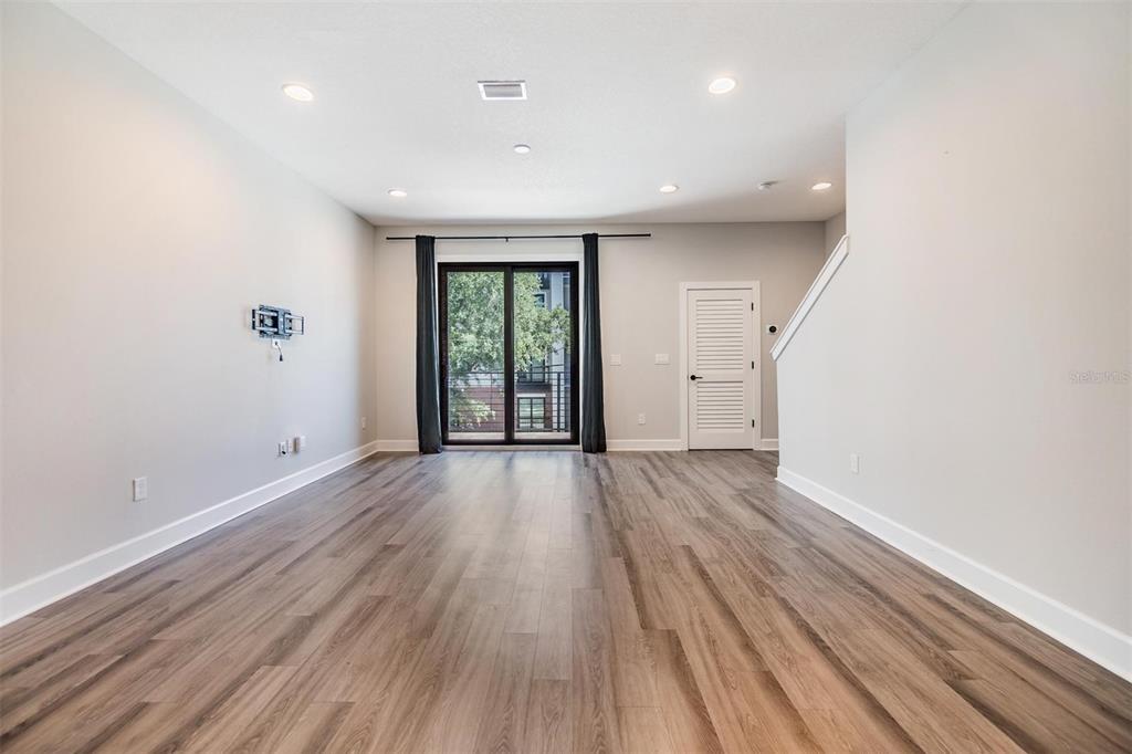 A living room with light gray walls, wood-look flooring, recessed lighting, and a sliding glass door — 1302 W CARMEN STREET UNIT 1, TAMPA, FL
