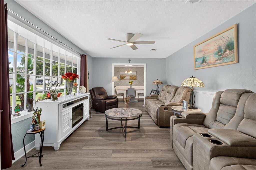 A living room features light gray walls, wood-look flooring, a ceiling fan, and beige furniture — 117 ANN RUSTIN DRIVE, ORMOND BEACH, FL