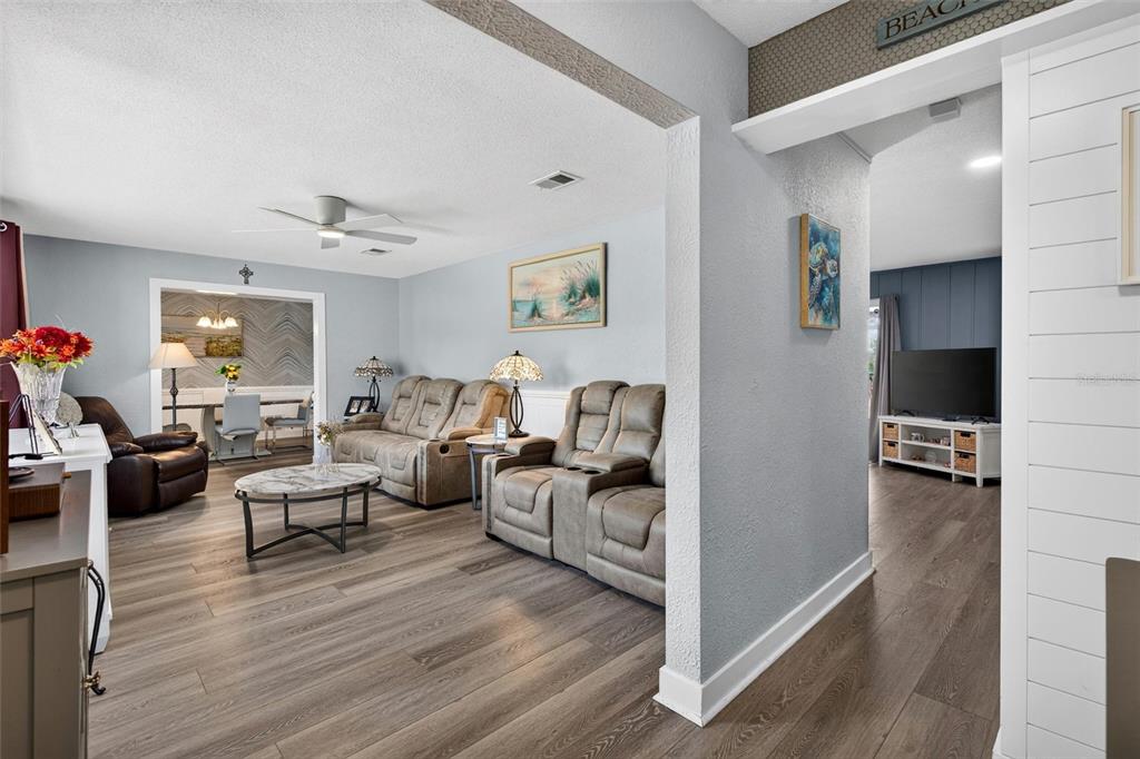 A living room with light gray walls, wood-look flooring, and a view into a dining area — 117 ANN RUSTIN DRIVE, ORMOND BEACH, FL