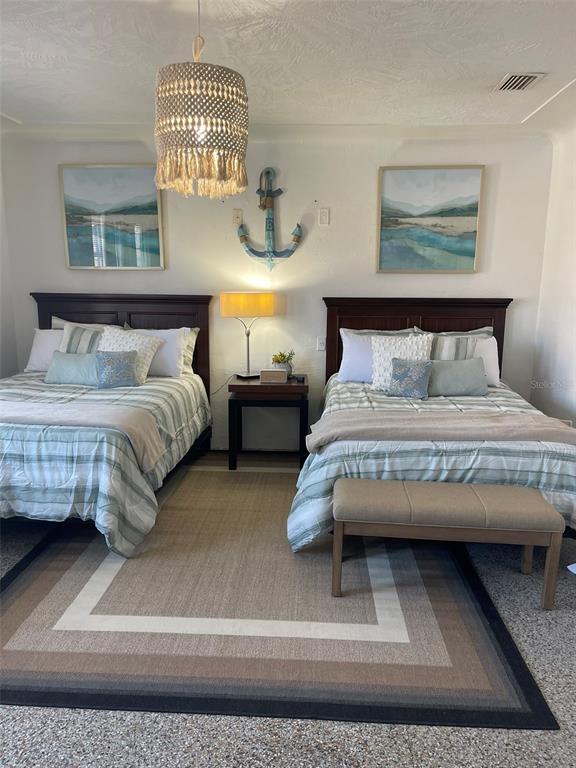 A bedroom features two beds with plaid bedding, a central nightstand, and coastal-themed wall decor — 128 RIDGEWOOD AVENUE, DAYTONA BEACH, FL
