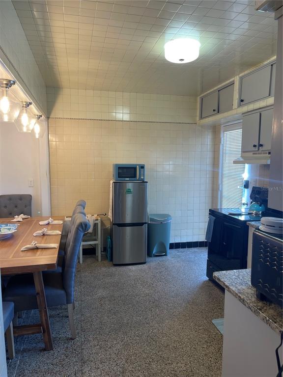 A kitchen with tiled walls and ceiling, a dining table, and stainless steel appliances — 128 RIDGEWOOD AVENUE, DAYTONA BEACH, FL