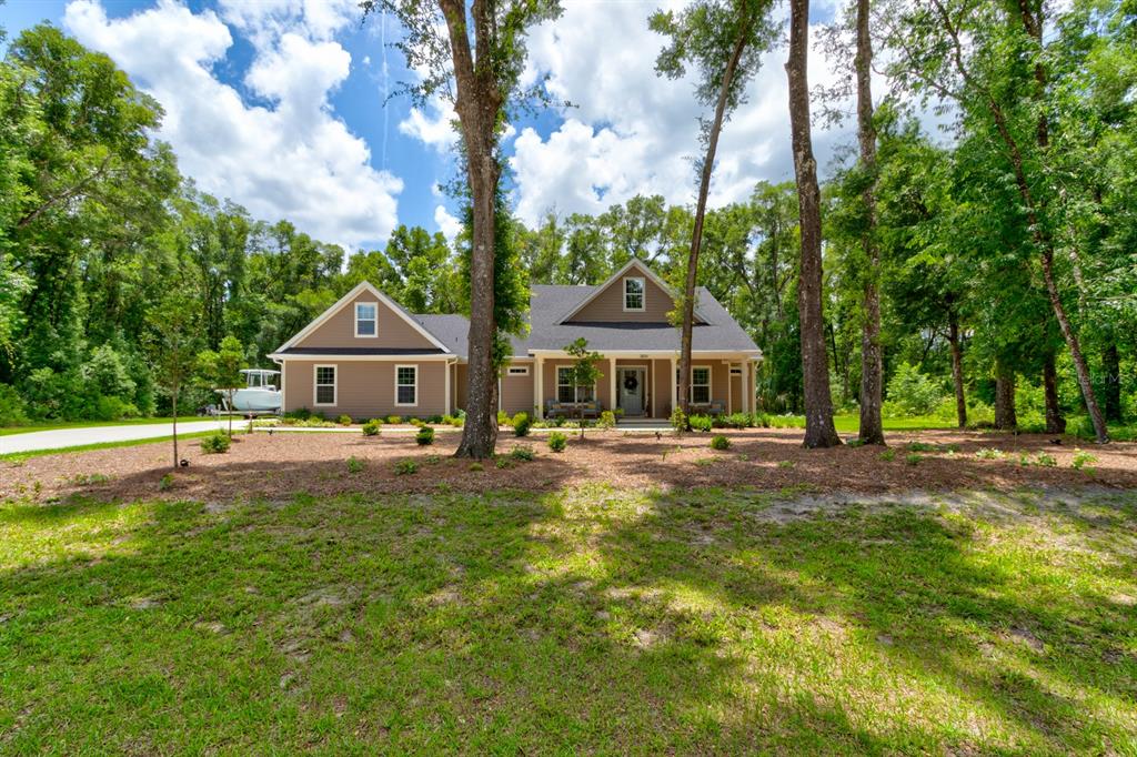 A tan house with a gabled roof sits in a wooded lot with a boat parked — 3504 DUNSTABLE DRIVE, DELAND, FL