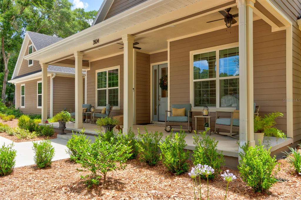A tan house with a covered front porch, rocking chairs, and landscaped front yard — 3504 DUNSTABLE DRIVE, DELAND, FL