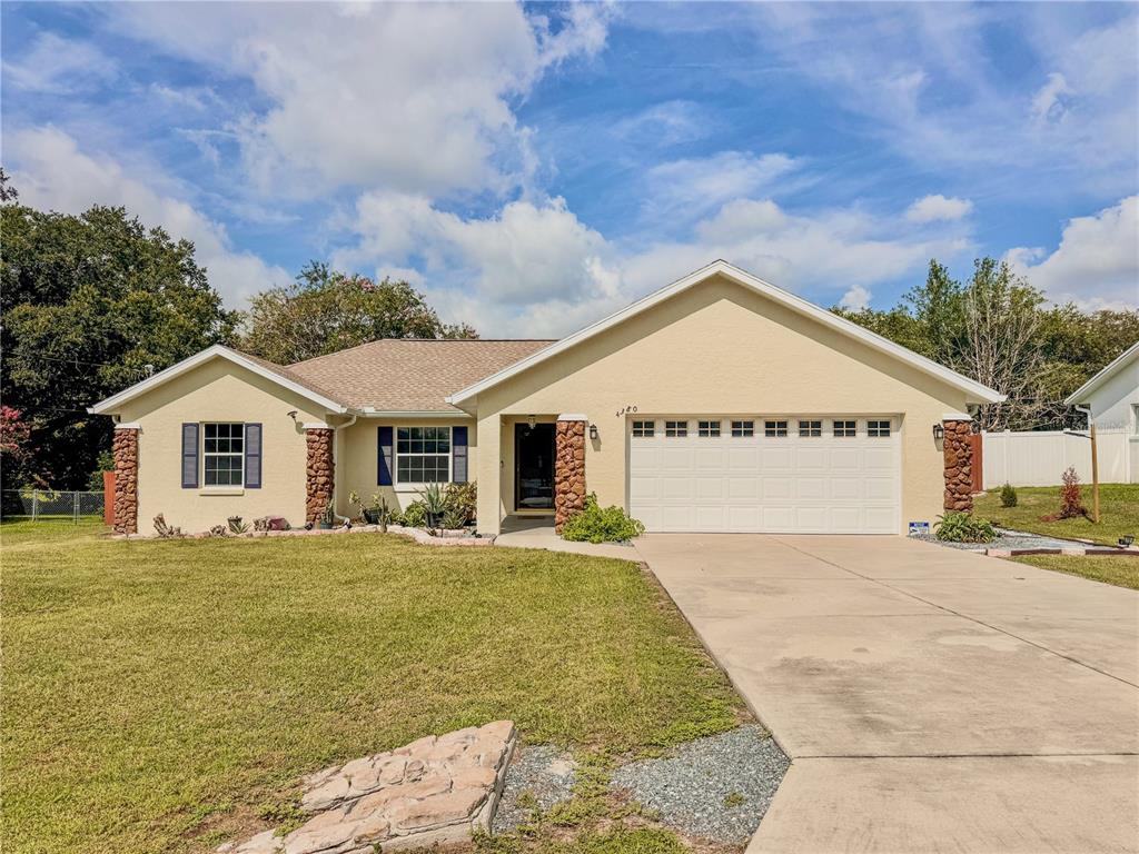 A single-story house with a beige stucco exterior, stone accents, and a two-car garage — 4380 NE 19TH AVENUE, OCALA, FL