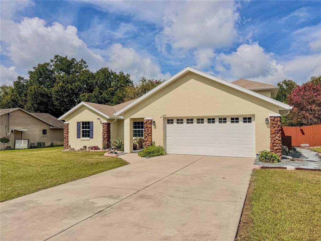 A single-story house with a beige stucco exterior, stone accents, and a two-car garage — 4380 NE 19TH AVENUE, OCALA, FL