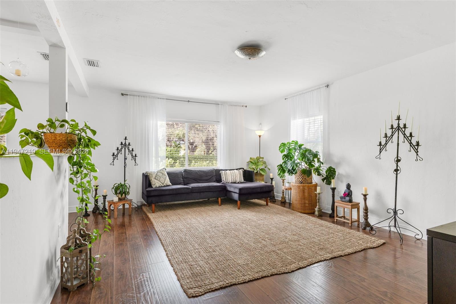 A living room features a dark sectional sofa, a large jute rug, and hardwood floors — 550 Cardinal St, Miami Springs FL 33166, MIAMI SPRINGS, FL