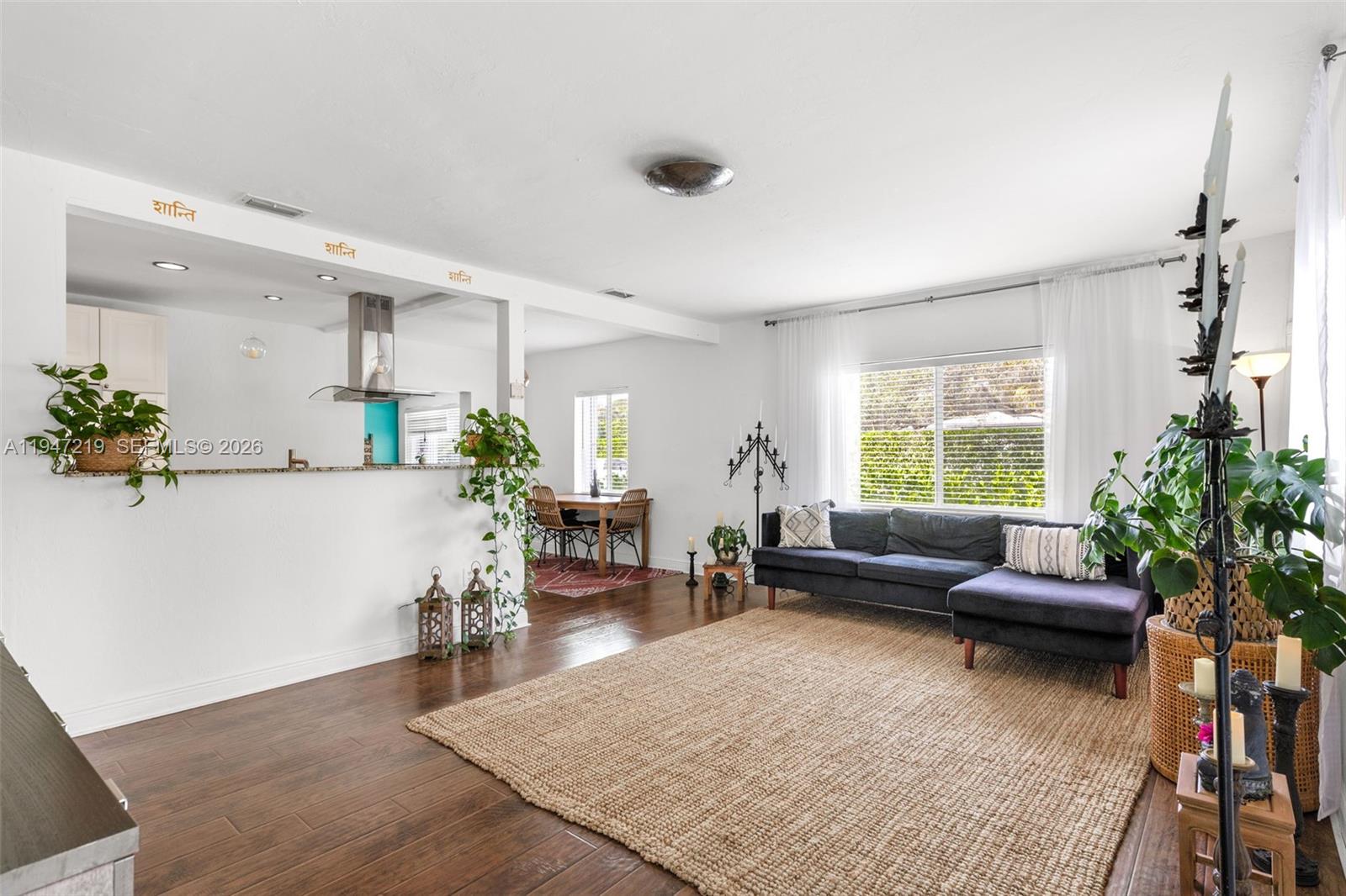 A living room with dark wood floors, a large jute rug, and a grey sectional sofa — 550 Cardinal St, Miami Springs FL 33166, MIAMI SPRINGS, FL