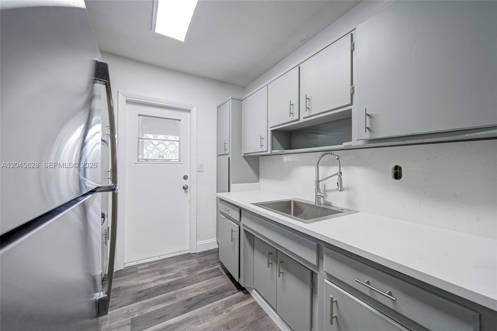 A kitchen features gray cabinets, white countertops, a stainless steel sink, and wood-look flooring — 6565 Santona St # B19, Coral Gables FL 33146, CORAL GABLES, FL