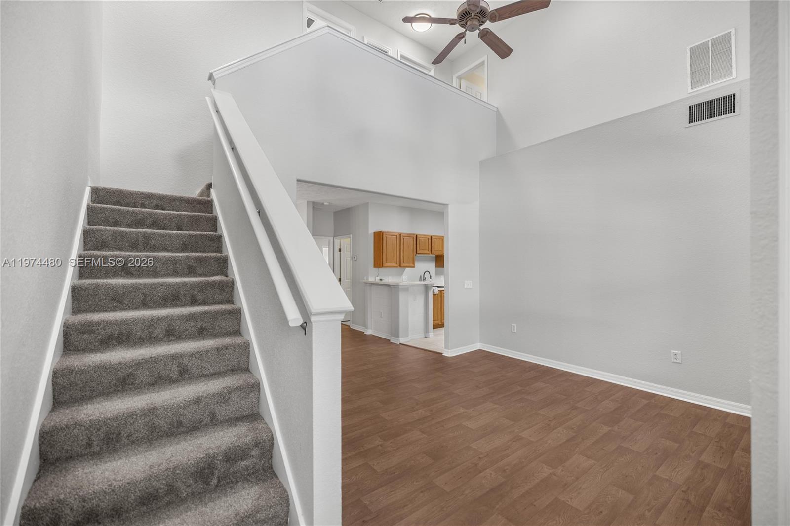 A carpeted staircase leads to a loft overlooking a living area with wood-look flooring — 231 NE 28th Ave Unit 103, Ocala FL 34470, OCALA, FL