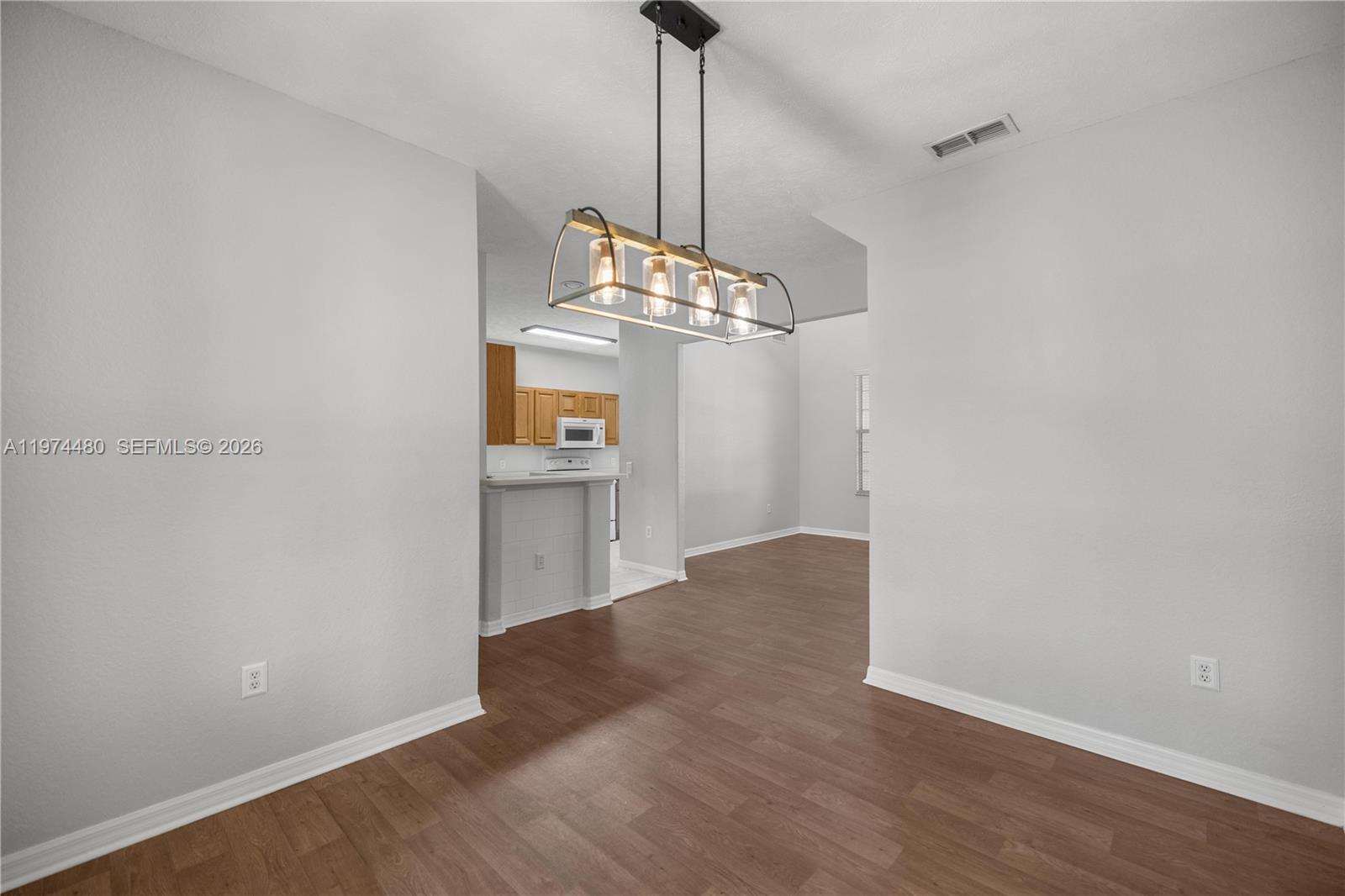 A dining area with wood-look flooring features a modern four-light pendant fixture above — 231 NE 28th Ave Unit 103, Ocala FL 34470, OCALA, FL