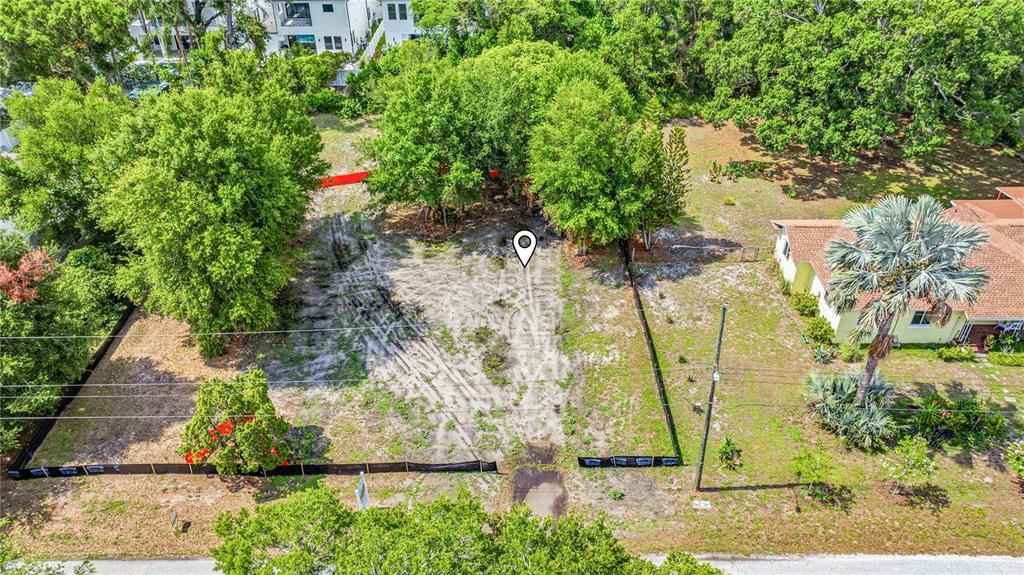 An aerial view of a cleared, fenced residential lot with mature trees and surrounding houses — 1019 W CORAL STREET, TAMPA, FL