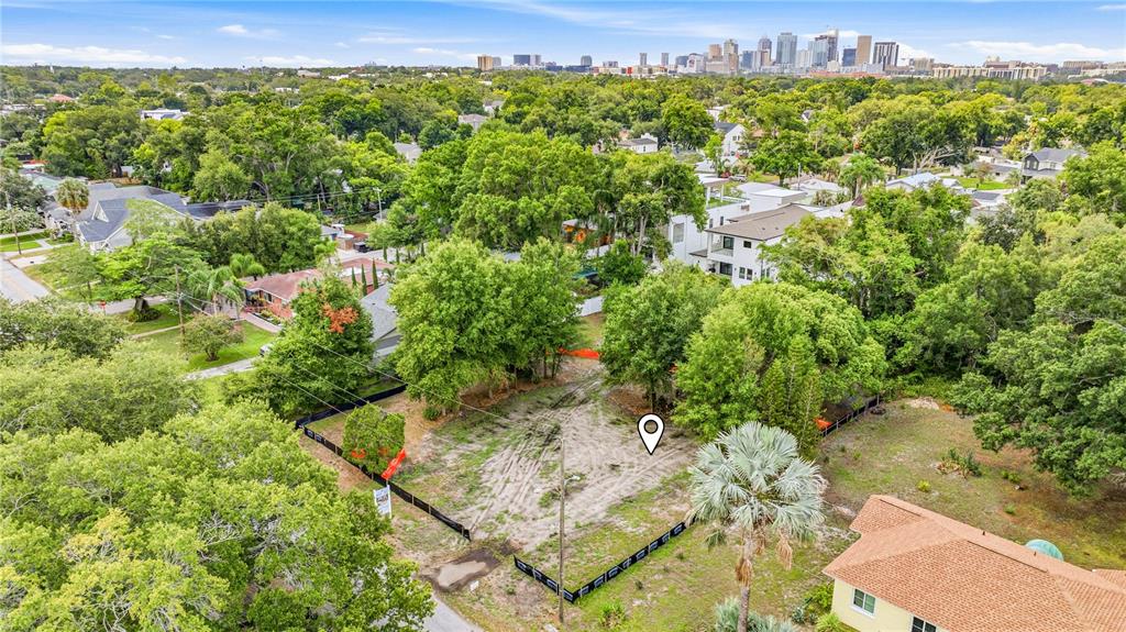 An aerial view shows a vacant, fenced-in residential lot surrounded by trees and nearby houses — 1019 W CORAL STREET, TAMPA, FL