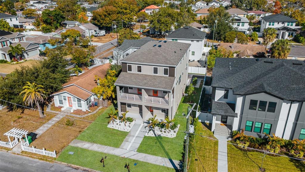 An aerial view of a three-story modern house situated between two smaller residential properties — 2711 W NORTH B STREET UNIT 2, TAMPA, FL
