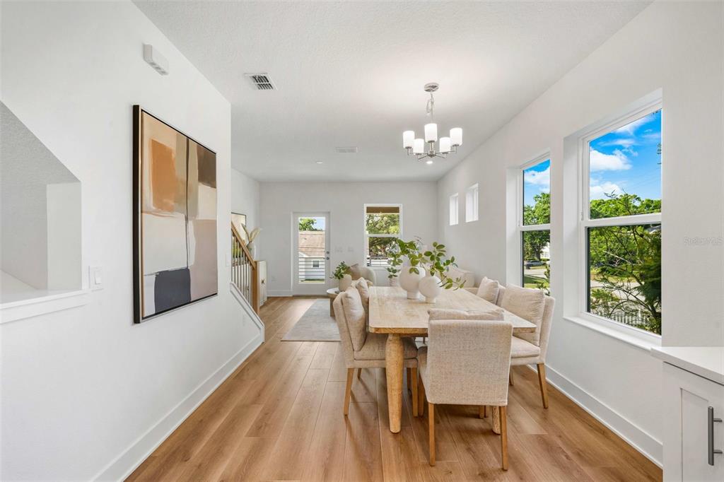 A dining area with a light wood table, upholstered chairs, and large windows — 2711 W NORTH B STREET UNIT 2, TAMPA, FL