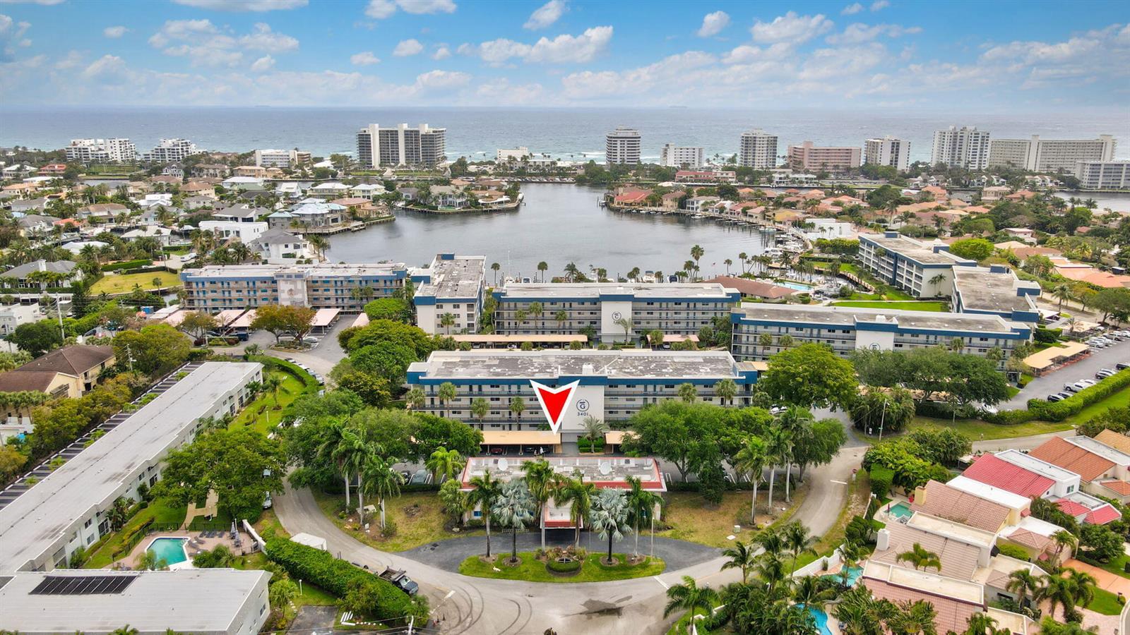 An aerial view shows a multi-story apartment complex with a red arrow pointing toward it — 3401 Spanish Trail # 151, Delray Beach FL 33483, DELRAY BEACH, FL