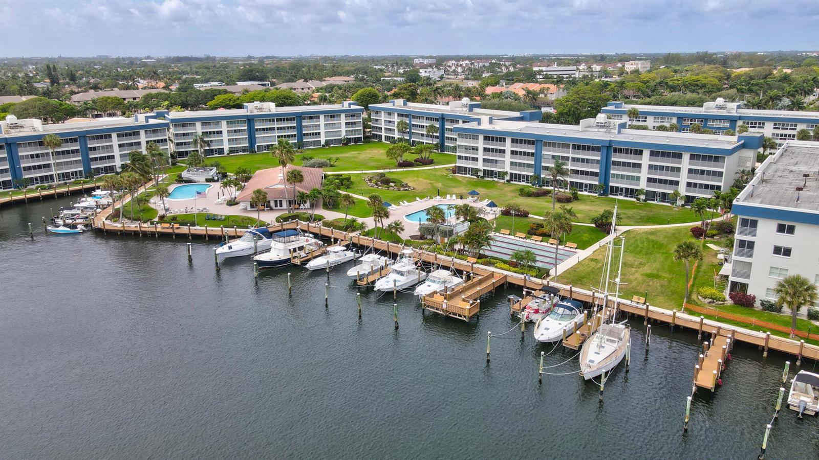 An aerial view shows a multi-story apartment complex with a marina and two swimming pools — 3401 Spanish Trail # 151, Delray Beach FL 33483, DELRAY BEACH, FL