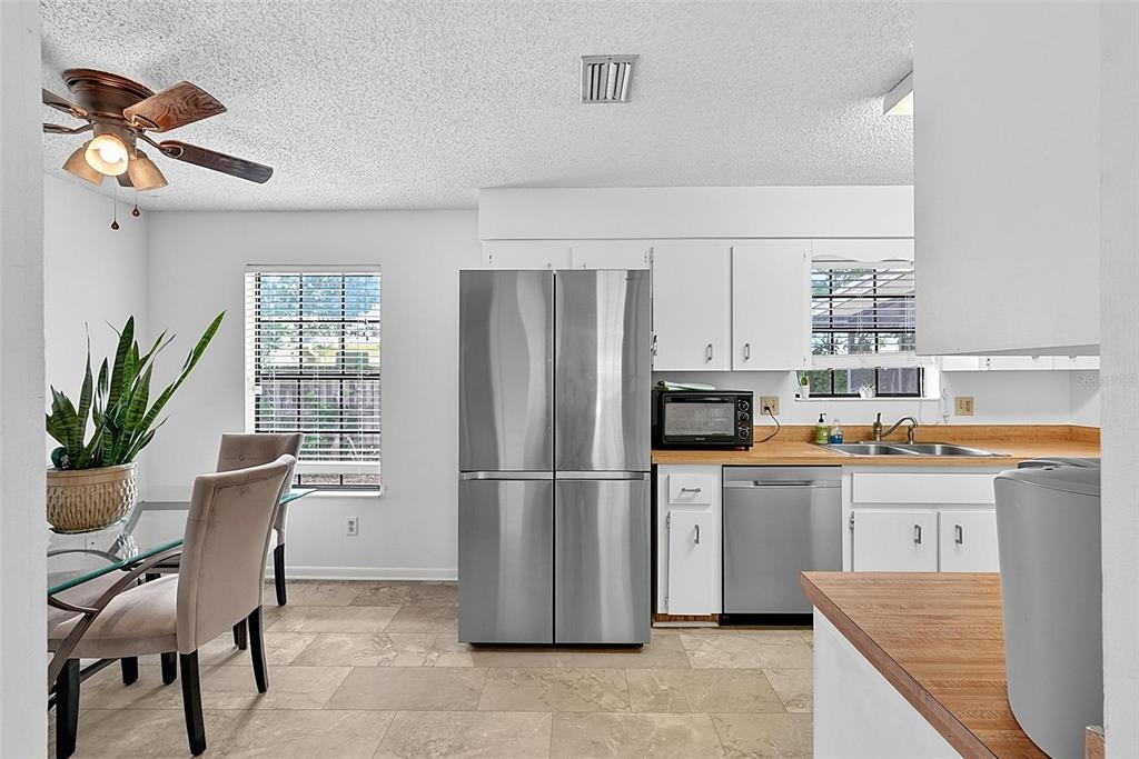 A kitchen and dining area with stainless steel appliances, white cabinets, and tile flooring — 9 BRIDGET TERRACE, ORMOND BEACH, FL