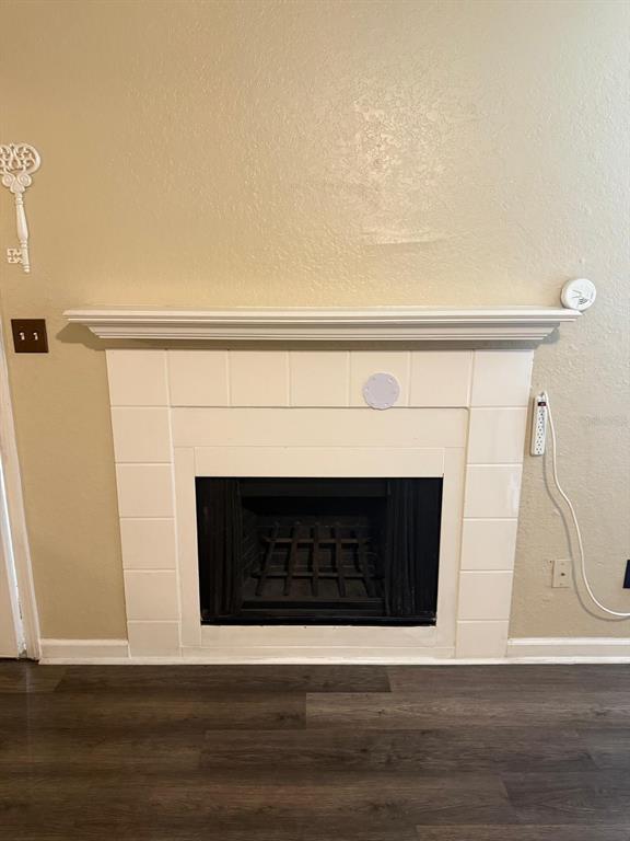 A fireplace with a white tile surround and mantel sits against a beige wall — 4400 THORNBRIAR LANE UNIT 102, ORLANDO, FL