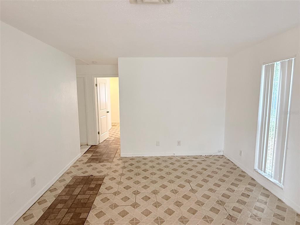 An empty room features white walls, a tiled floor, and a window with vertical blinds — 1100 70TH STREET N UNIT 4, ST PETERSBURG, FL