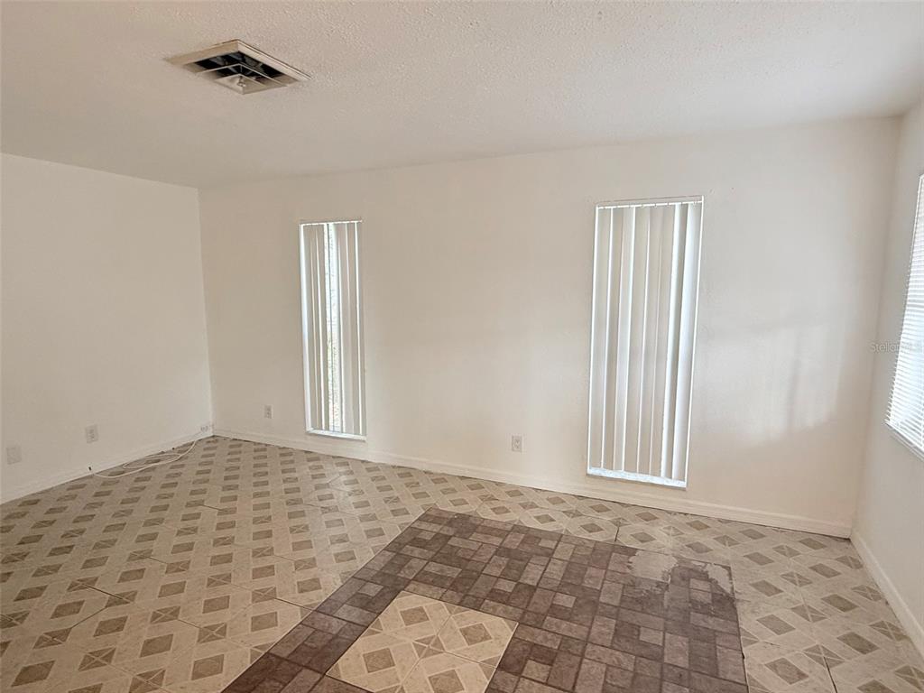 An empty room features white walls, vertical blinds on two windows, and patterned tile flooring — 1100 70TH STREET N UNIT 4, ST PETERSBURG, FL