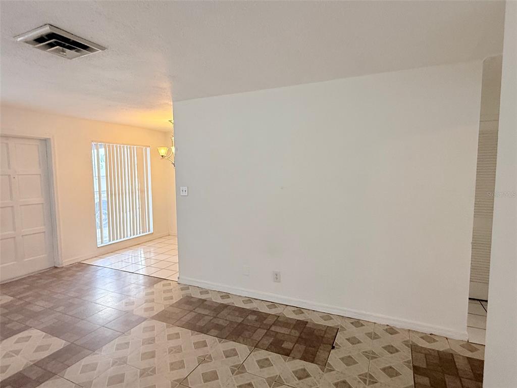 An interior view shows a tiled room with a large blank wall and a window — 1100 70TH STREET N UNIT 4, ST PETERSBURG, FL