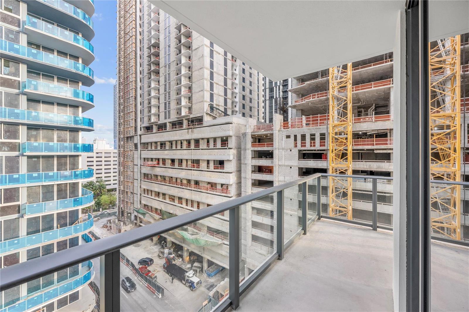 A balcony view overlooking a busy urban construction site with multiple high-rise buildings — 11 NE 6th Street # 907, Miami FL 33132, MIAMI, FL