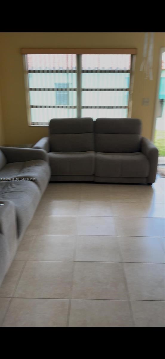 A living room features light-colored tile flooring and two gray sofas facing a window — 18 SW 13th St, Dania Beach FL 33004, DANIA BEACH, FL