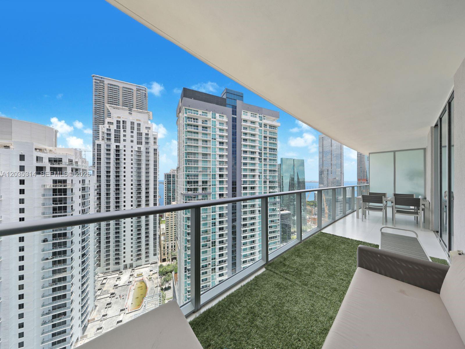 A balcony with artificial turf, outdoor furniture, and a view of surrounding high-rise buildings — 1100 S Miami Ave # 3411, Miami FL 33130, MIAMI, FL