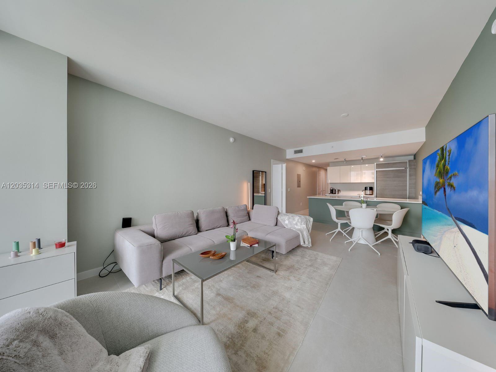 A living room with a sectional sofa, coffee table, and dining area near a kitchen — 1100 S Miami Ave # 3411, Miami FL 33130, MIAMI, FL