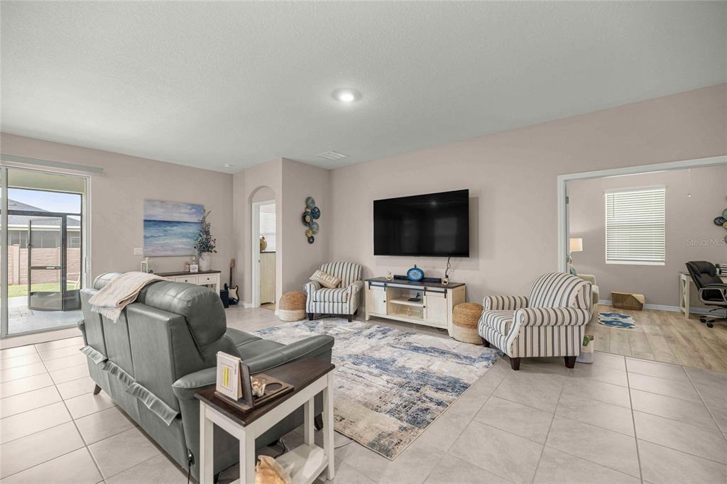 A living room features a grey sofa, two striped armchairs, and a wall-mounted television — 4312 NW 55TH COURT, OCALA, FL