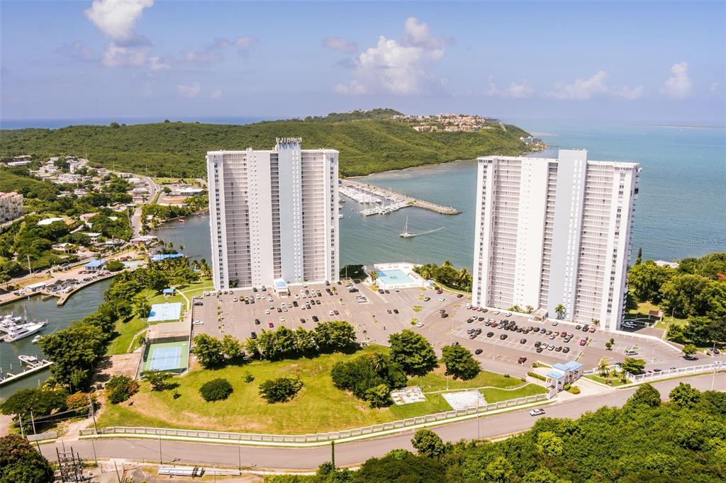 An aerial view shows two tall residential towers situated near a marina and coastline — 200 AVENIDA MARINA VIEW DOS MARINAS II UNIT 2706, FAJARDO, PR