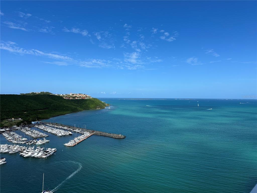 An aerial view shows a marina with many boats docked along a pier near a coastline — 200 AVENIDA MARINA VIEW DOS MARINAS II UNIT 2706, FAJARDO, PR