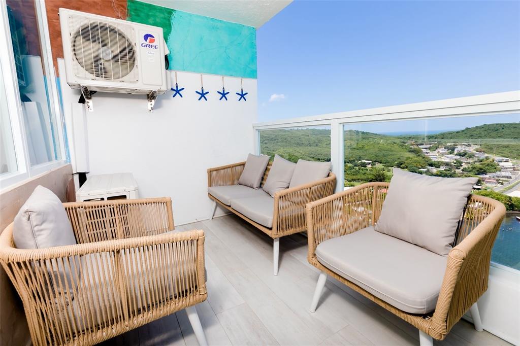 A balcony features wicker-style seating, a Gree air conditioning unit, and a scenic landscape view — 200 AVENIDA MARINA VIEW DOS MARINAS II UNIT 2706, FAJARDO, PR