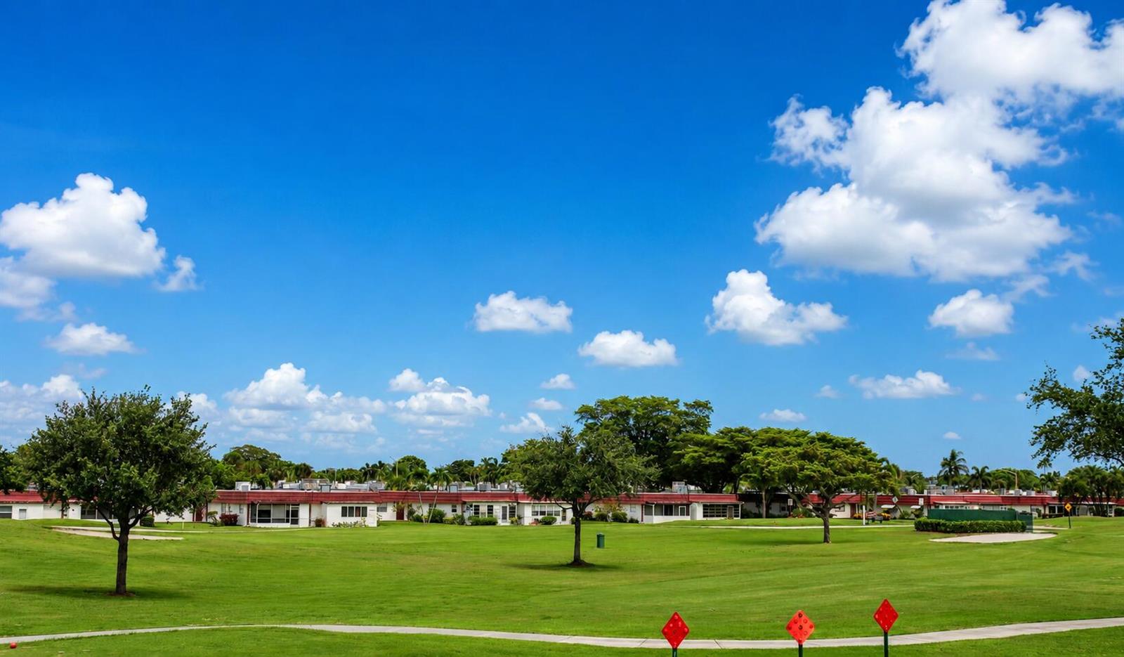 A grassy lawn with trees in front of a long, single-story residential building — 148 Tuscany # B, Delray Beach FL 33446, DELRAY BEACH, FL