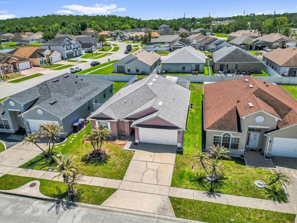 An aerial view shows a suburban street with single-family homes and manicured lawns — 1804 BAGUETTE COURT, KISSIMMEE, FL