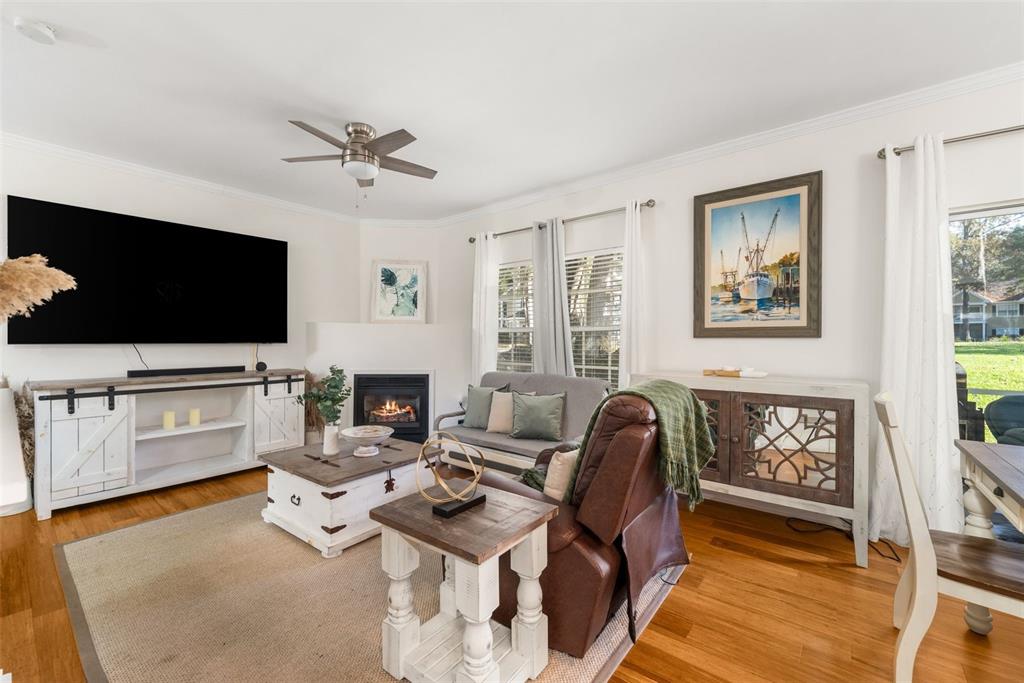 A living room features a fireplace, a large television, a brown recliner, and wood flooring — 10000 SW 52ND AVENUE UNIT 35, GAINESVILLE, FL